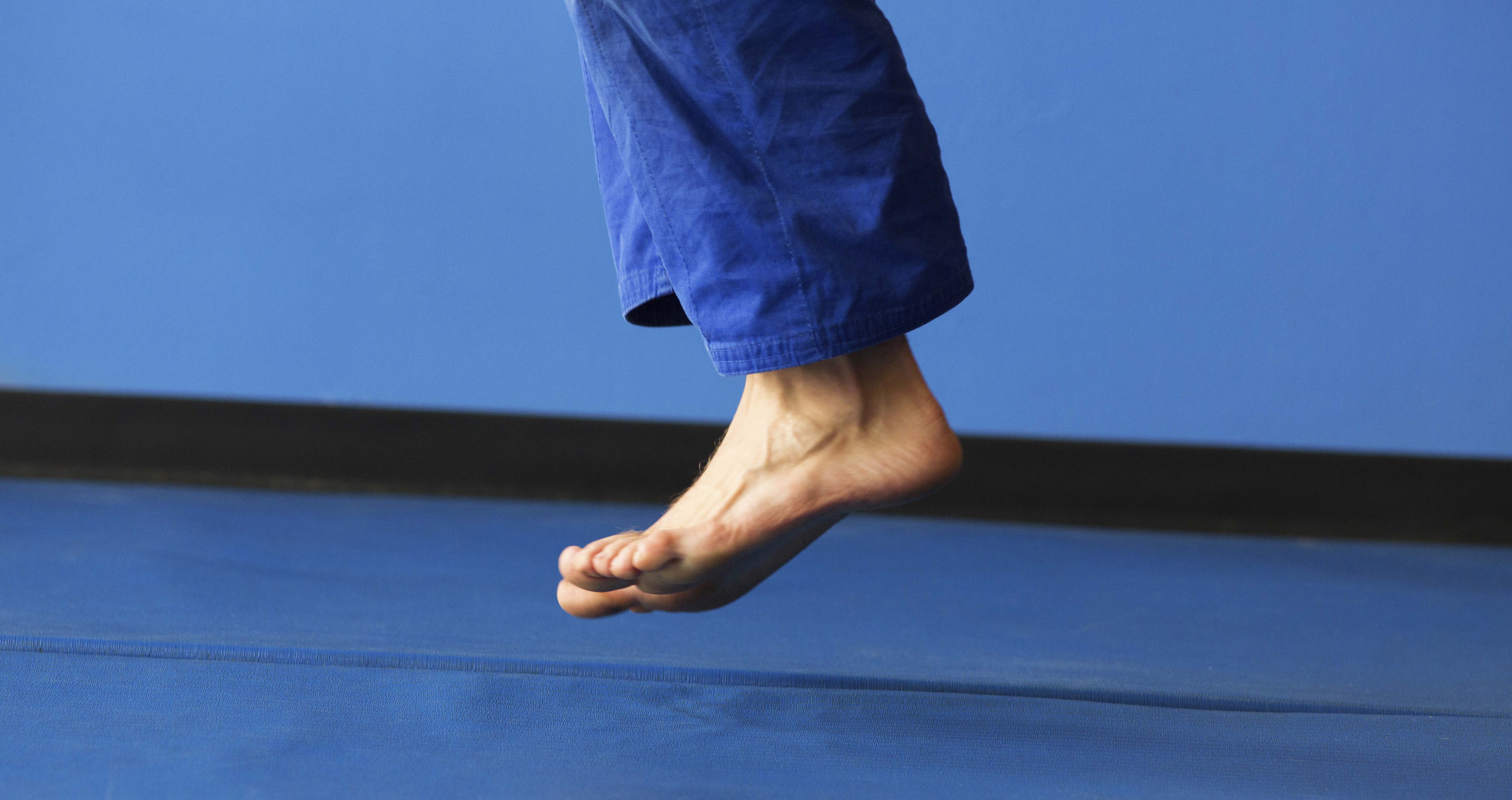 Feet jumping over blue sports mat Performancetypes